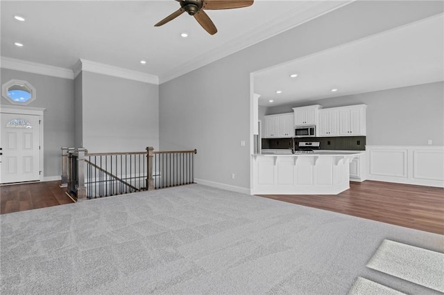 unfurnished living room featuring ornamental molding, dark colored carpet, baseboards, and recessed lighting