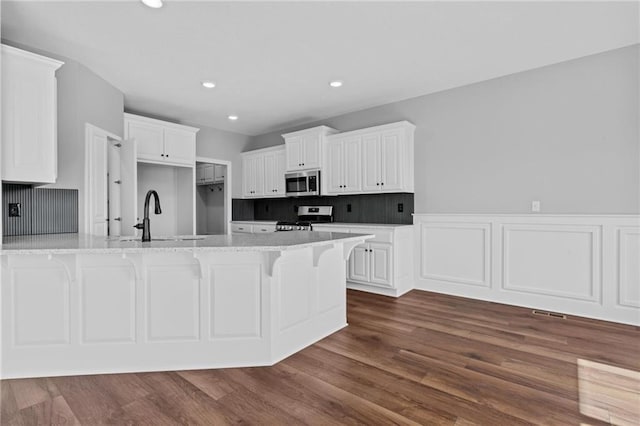 kitchen with dark wood-style floors, appliances with stainless steel finishes, white cabinets, a sink, and a peninsula