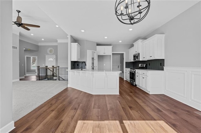 kitchen featuring a peninsula, appliances with stainless steel finishes, dark wood-type flooring, and visible vents