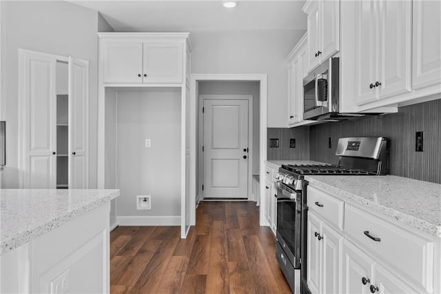 kitchen with stainless steel appliances, dark wood-style flooring, white cabinetry, and light stone countertops