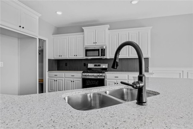 kitchen featuring stainless steel appliances, recessed lighting, white cabinetry, and light stone countertops