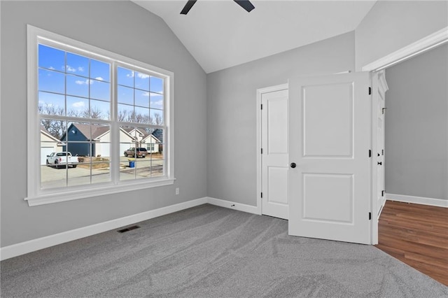 unfurnished bedroom featuring carpet floors, visible vents, vaulted ceiling, ceiling fan, and baseboards