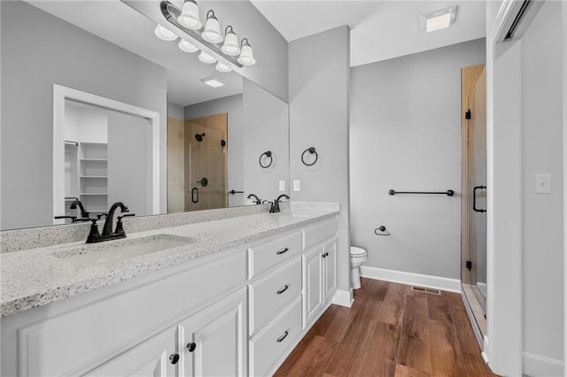 bathroom with a stall shower, baseboards, a sink, and wood finished floors