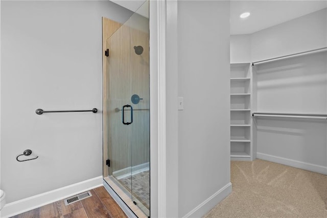 bathroom with toilet, a stall shower, visible vents, and baseboards