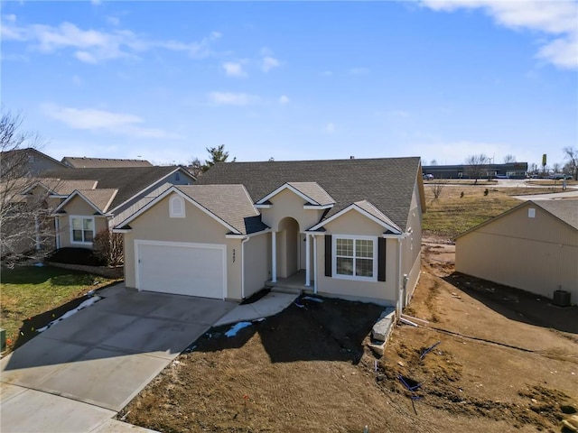 single story home featuring a shingled roof, driveway, an attached garage, and stucco siding