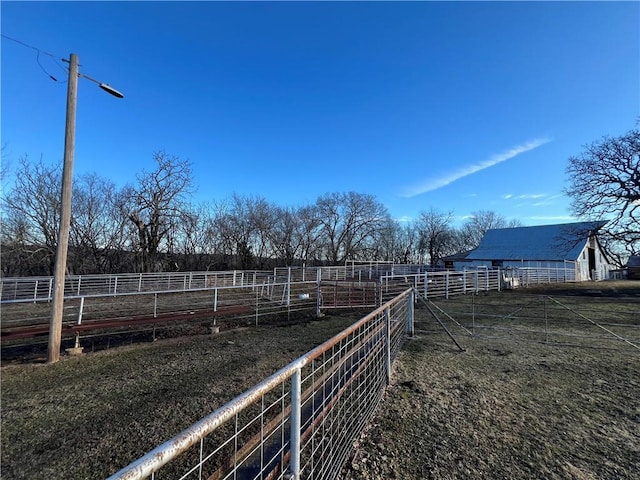 view of yard featuring fence, an outbuilding, and a rural view