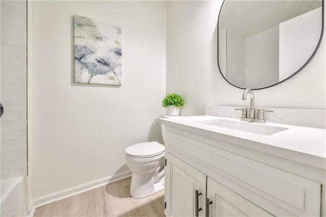 full bath featuring toilet, wood finished floors, vanity, baseboards, and shower / bathing tub combination