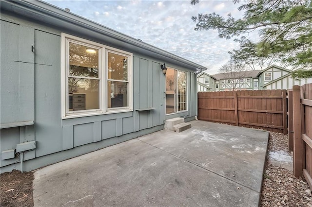 view of side of home with fence, board and batten siding, and a patio