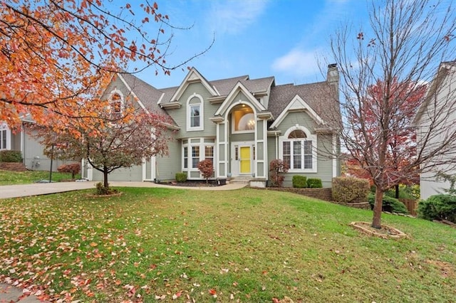 view of front facade with driveway, a chimney, and a front lawn