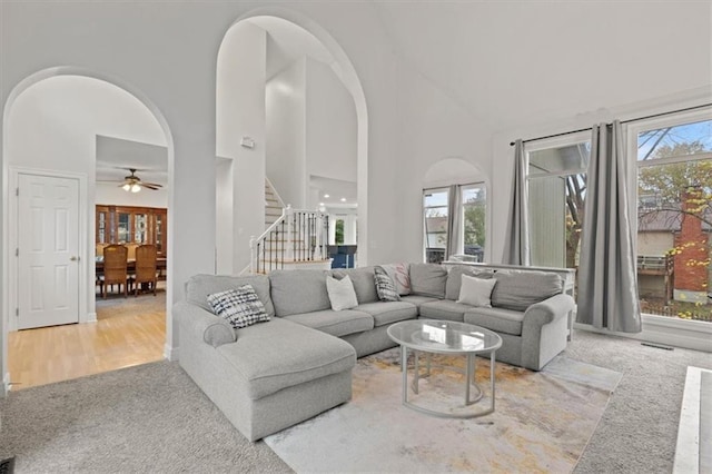 living room with stairs, a high ceiling, and arched walkways