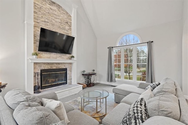 carpeted living room with high vaulted ceiling, a glass covered fireplace, and baseboards