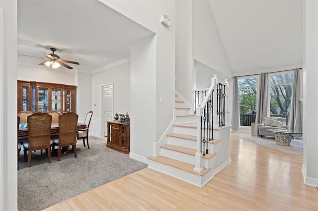 interior space featuring light wood-type flooring, ceiling fan, stairway, and baseboards