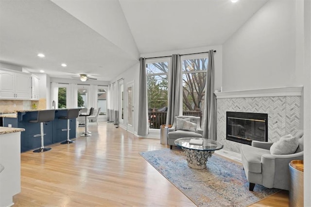 living area featuring recessed lighting, a tiled fireplace, light wood-style floors, vaulted ceiling, and ceiling fan