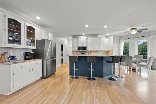 kitchen featuring glass insert cabinets, light wood-style floors, white cabinetry, and stainless steel appliances