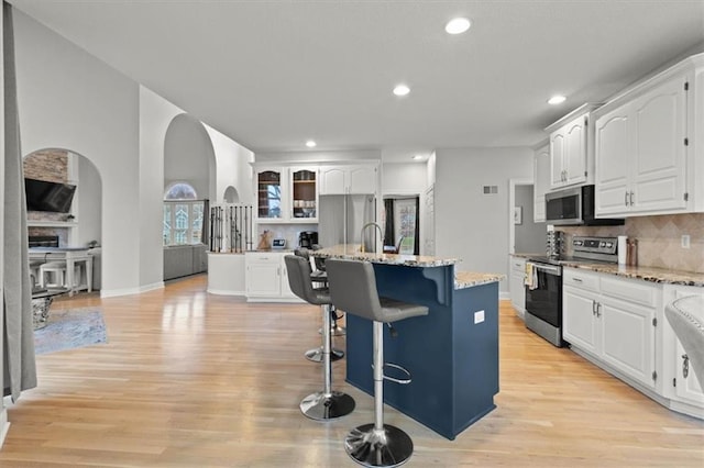 kitchen with light wood-style flooring, white cabinetry, stainless steel appliances, and backsplash