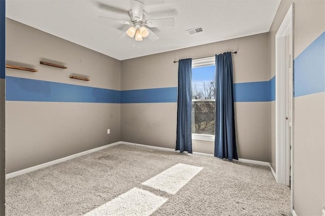 spare room with baseboards, carpet flooring, visible vents, and a ceiling fan