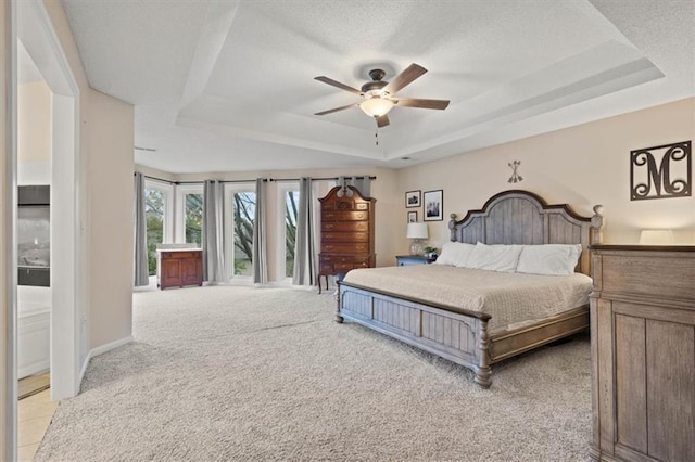 bedroom featuring a raised ceiling, light carpet, ceiling fan, a textured ceiling, and baseboards