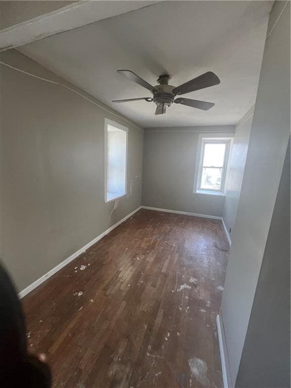 empty room featuring ceiling fan, dark wood-style flooring, and baseboards