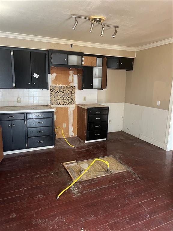 kitchen featuring crown molding, light countertops, dark wood finished floors, and decorative backsplash