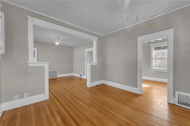 spare room featuring ceiling fan, visible vents, light wood-style flooring, and crown molding