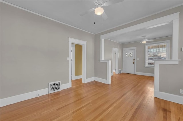 empty room with baseboards, ornamental molding, visible vents, and light wood-style floors