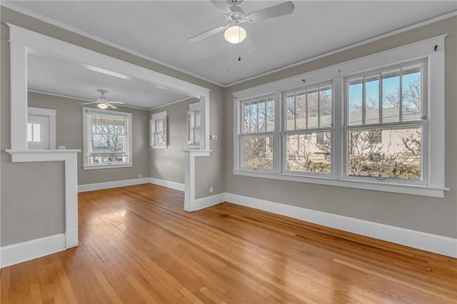 interior space with baseboards, light wood-style floors, a ceiling fan, and crown molding