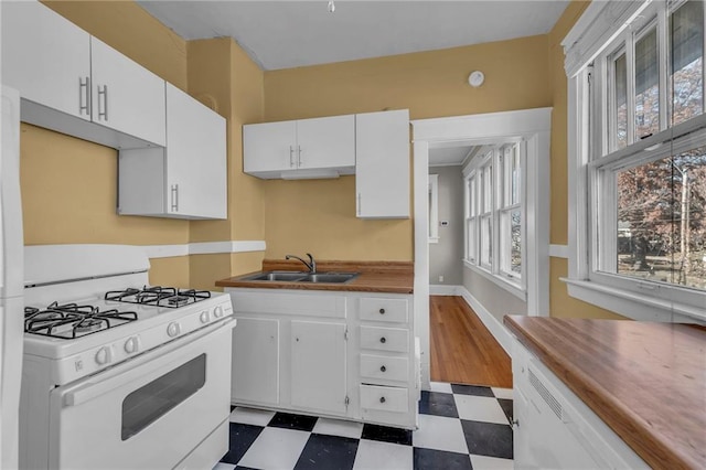 kitchen featuring dark floors, white cabinets, and gas range gas stove