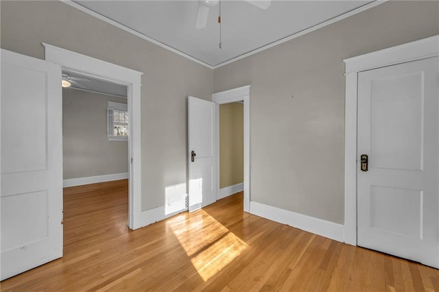 unfurnished bedroom with a ceiling fan, crown molding, light wood-style flooring, and baseboards