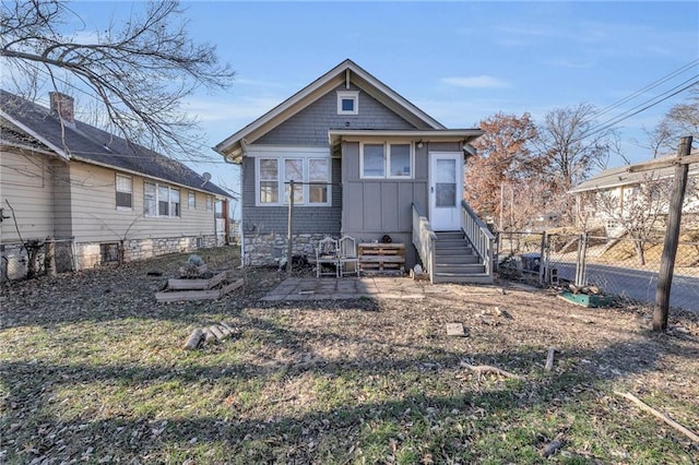 rear view of house with entry steps, fence, board and batten siding, and a patio