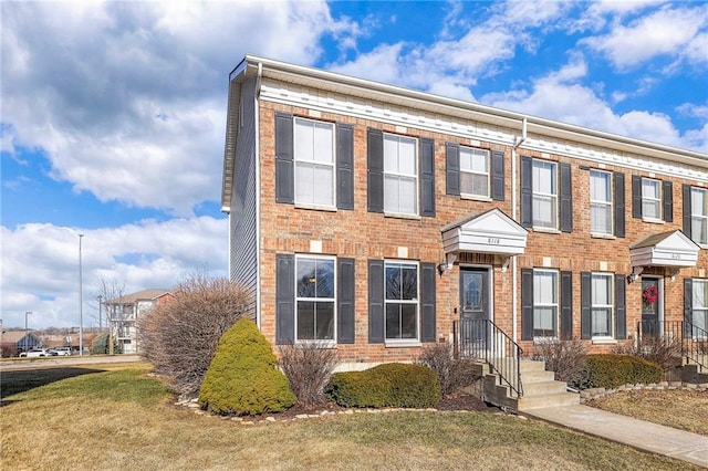 multi unit property featuring a front yard and brick siding