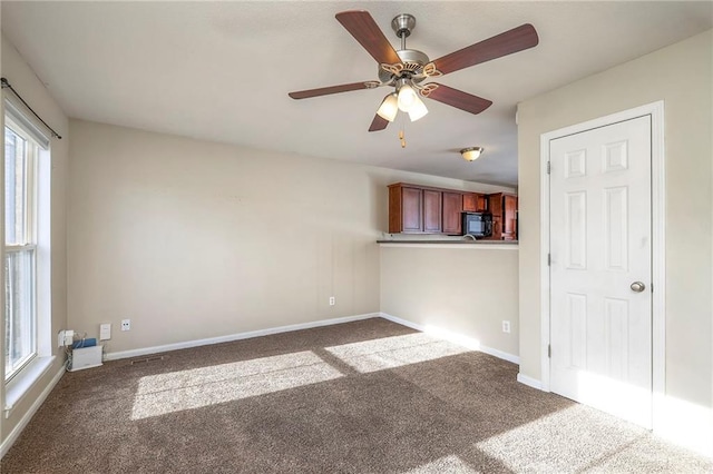 carpeted spare room featuring ceiling fan and baseboards