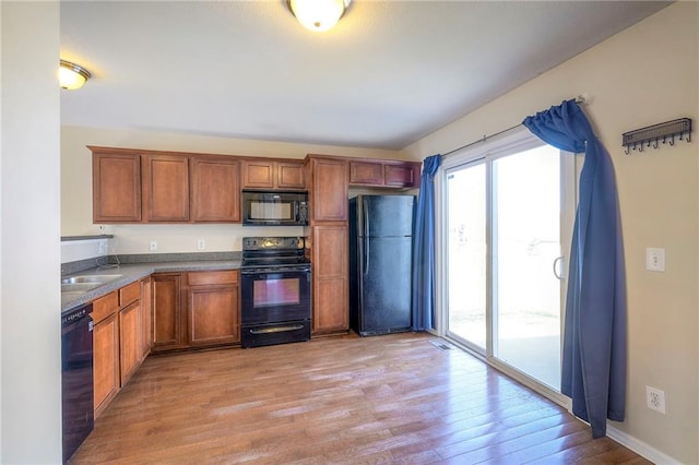 kitchen with black appliances, light wood-style flooring, baseboards, and brown cabinetry