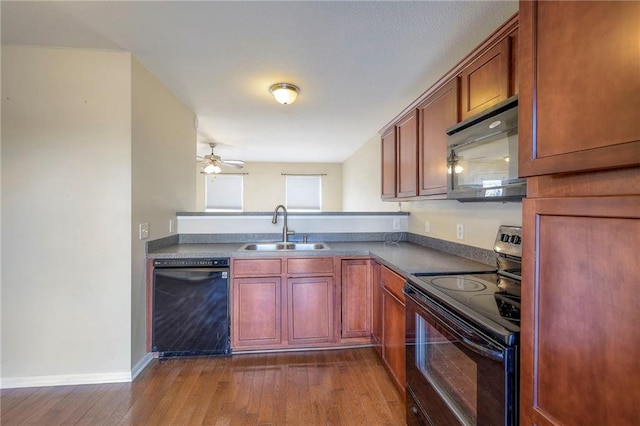 kitchen featuring dark countertops, black appliances, dark wood-style floors, and a sink