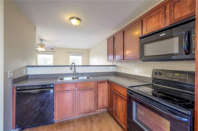 kitchen with a ceiling fan, dark countertops, light wood-type flooring, black appliances, and a sink