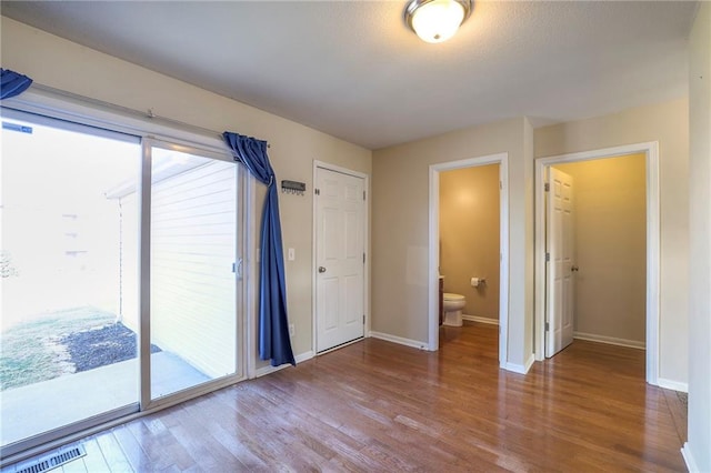 empty room featuring a healthy amount of sunlight, baseboards, visible vents, and wood finished floors