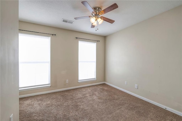 carpeted spare room featuring baseboards, visible vents, and a ceiling fan