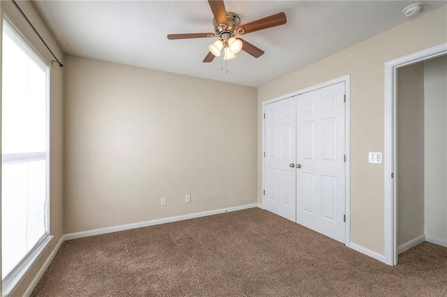 unfurnished bedroom with ceiling fan, a closet, baseboards, and carpet flooring