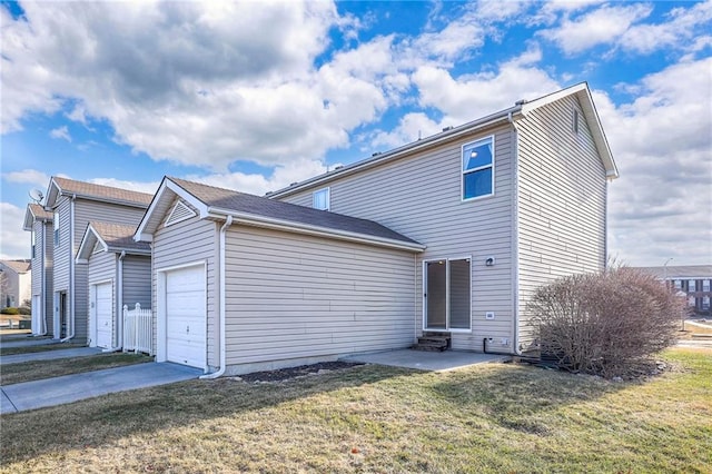 rear view of house featuring a garage, entry steps, driveway, and a yard