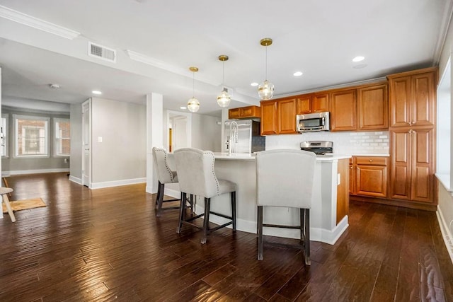 kitchen with stainless steel appliances, visible vents, light countertops, an island with sink, and pendant lighting