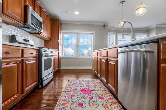 kitchen with stainless steel appliances, brown cabinets, ornamental molding, and decorative light fixtures