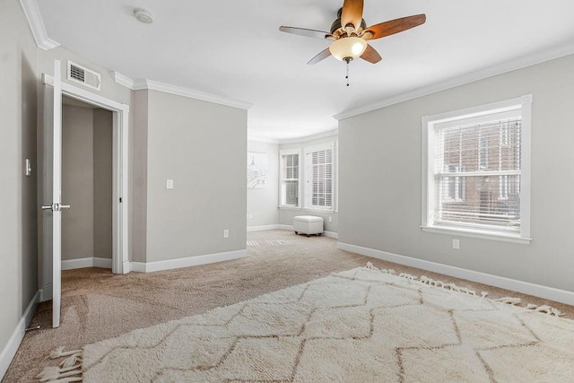 unfurnished bedroom featuring baseboards, visible vents, a ceiling fan, light colored carpet, and ornamental molding