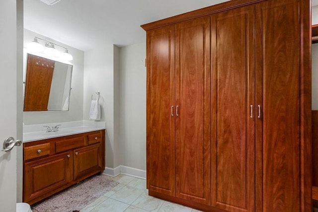 bathroom featuring baseboards, a closet, vanity, and tile patterned floors