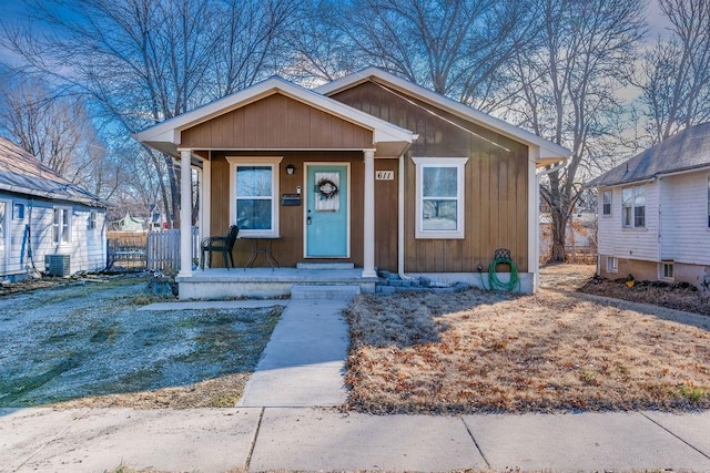 bungalow-style home featuring central air condition unit, fence, and a porch