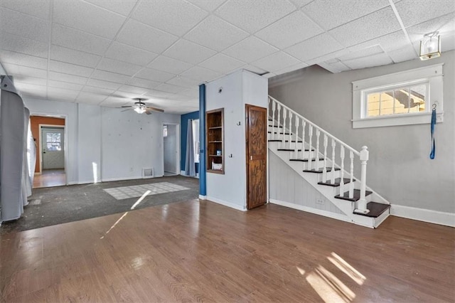 interior space with a paneled ceiling, wood finished floors, baseboards, and stairs