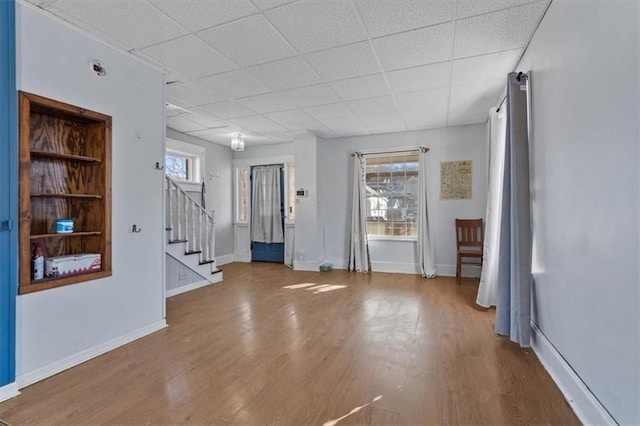 entryway with plenty of natural light, stairway, baseboards, and wood finished floors