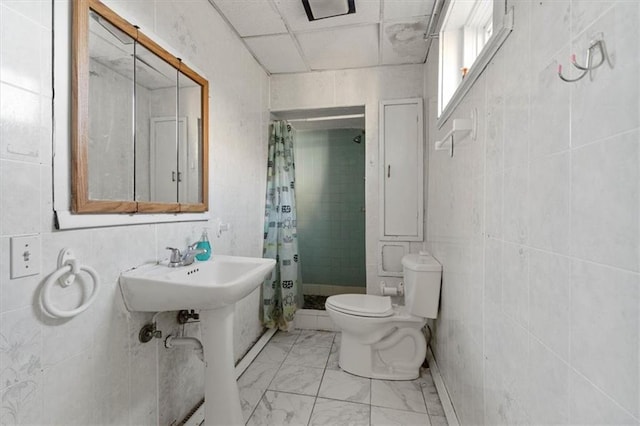 full bath with marble finish floor, tiled shower, tile walls, and toilet