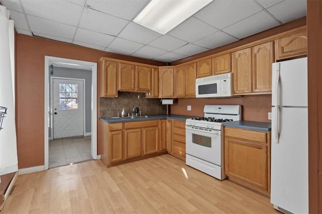 kitchen with white appliances, tasteful backsplash, a drop ceiling, dark countertops, and light wood-style flooring