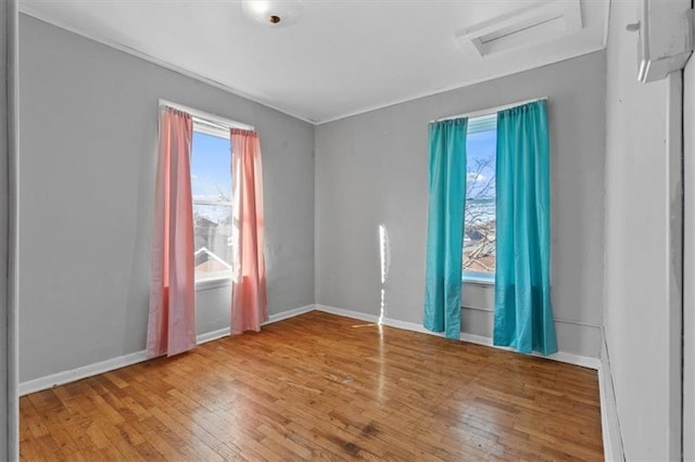 spare room with hardwood / wood-style floors, attic access, and baseboards