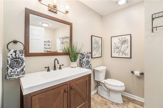 half bath with toilet, vanity, and baseboards