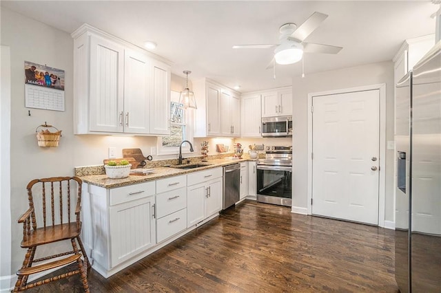 kitchen with light stone counters, white cabinetry, stainless steel appliances, and a sink